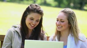 stock-footage-happy-young-women-using-a-laptop-in-a-park